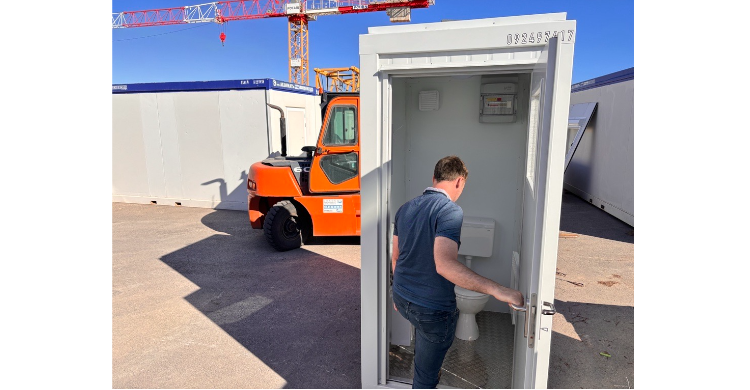 Un module Sanibox d'Allomat, module sanitaire avec un toilette, un lavabo, un panneau électrique en haut à droite et un miroir sur le mur de gauche au-dessus du lavabo.