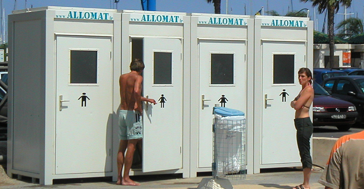 Un module Sanibox d'Allomat, module sanitaire avec un toilette, un lavabo, un panneau électrique en haut à droite et un miroir sur le mur de gauche au-dessus du lavabo.