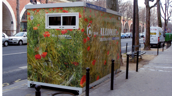 Un petit module de chantier avec un covering de champs avec des coquelicots, installé sur une place de parking, ce qui est son principal avantage.