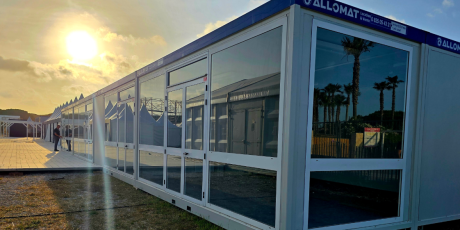 Bungalow modulaire vitré avec baies vitrées, destiné à un usage événementiel ou à un espace temporaire aménagé.