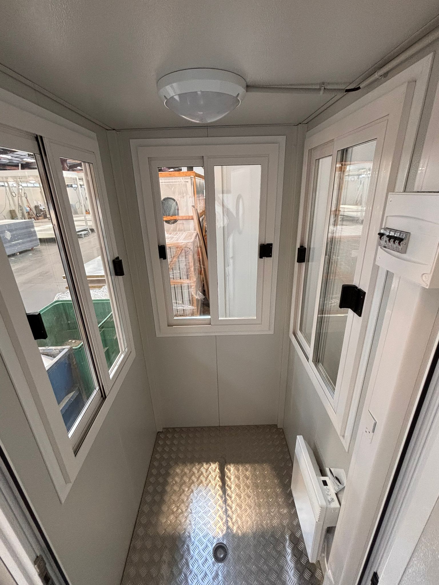 Intérieur d’une guérite Vigimat modulaire avec porte, fenêtres et aménagement compact pour module de chantier.