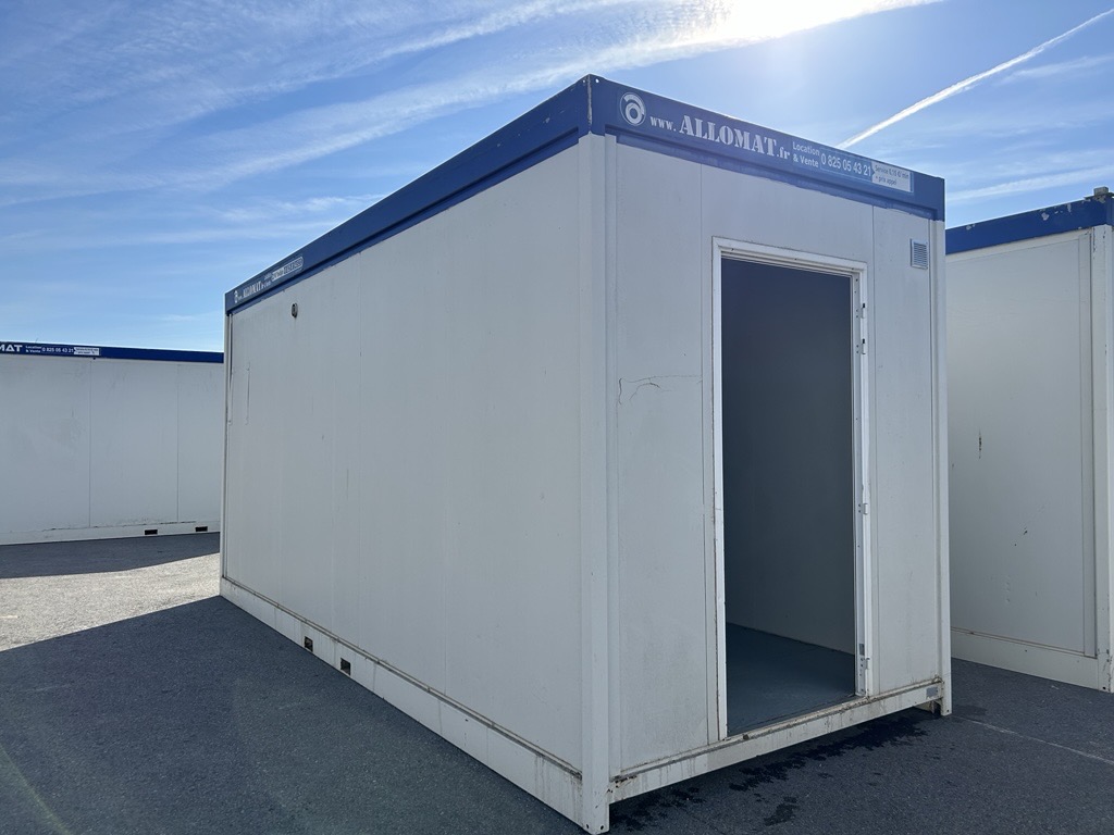 Bungalow sanitaire demi-domino installé sur chantier, avec porte d’accès et structure modulaire pour base vie ou sanitaires de chantier.