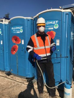Technicien Allomat en EPI r&eacute;alisant l'entretien et la d&eacute;sinfection des WC chimiques.