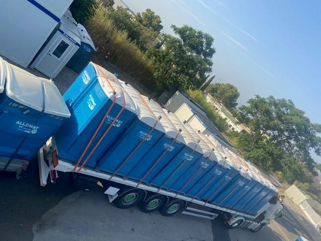 Lots de WC chimiques Allomat sanglés sur semi-remorque pour la location.