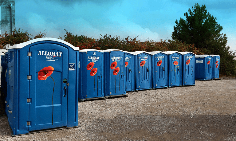 Longue rangée de cabines de WC mobiles bleues Allomat décorées de coquelicots.