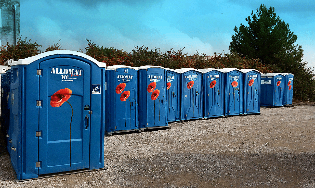 Longue rangée de cabines de WC mobiles bleues Allomat décorées de coquelicots.