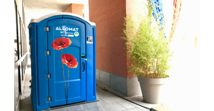 WC chimique autonome Allomat bleu décoré de coquelicots, installé pour un événement.
