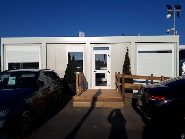 Module de type bureau de chantier avec porte vitrée et petite rampe d'accès en bois.