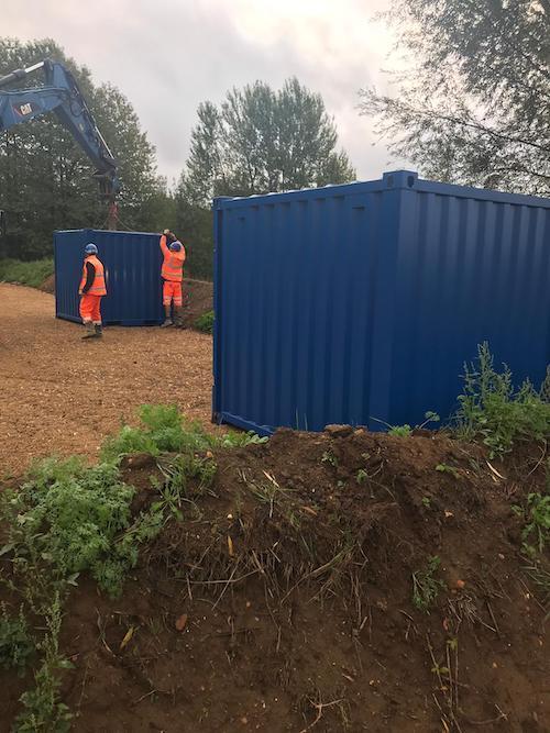 Ouvriers installant un conteneur bleu, illustrant un service de conteneur location.