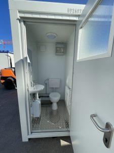Vue intérieure d'un bloc sanitaire modulaire de chantier avec WC, lavabo et chauffage.