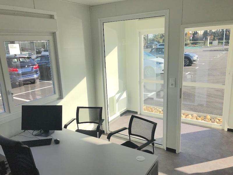 Bureau préfabriqué aménagé avec vue sur le parking.
