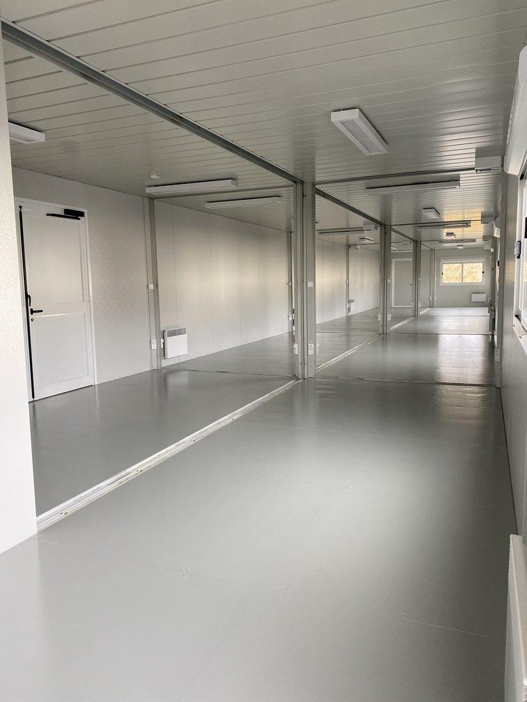 Long couloir intérieur de modules alignés, idéal pour bureau open-space ou location conteneur de stockage.