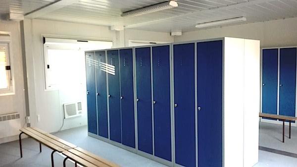 Vestiaire modulaire avec casiers bleus et bancs. Équipement disponible en location bureau modulaire.