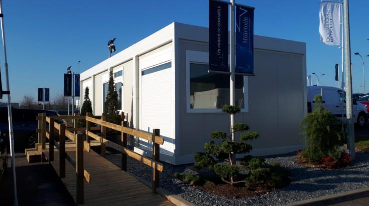 Bureau de chantier modulaire avec rampe d'accès en bois et aménagement paysager.