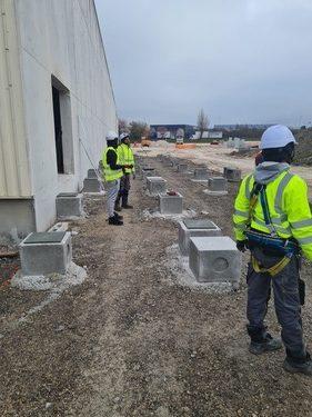 Ouvriers sur chantier préparant les plots de fondation pour l'installation de conteneur de stockage.