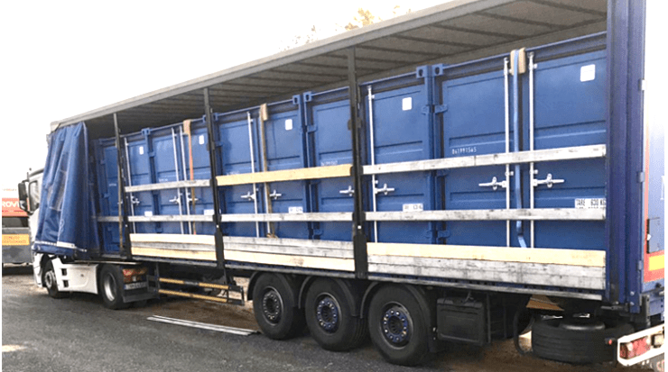 Camion transportant plusieurs conteneurs bleus pour la location de conteneur de stockage.